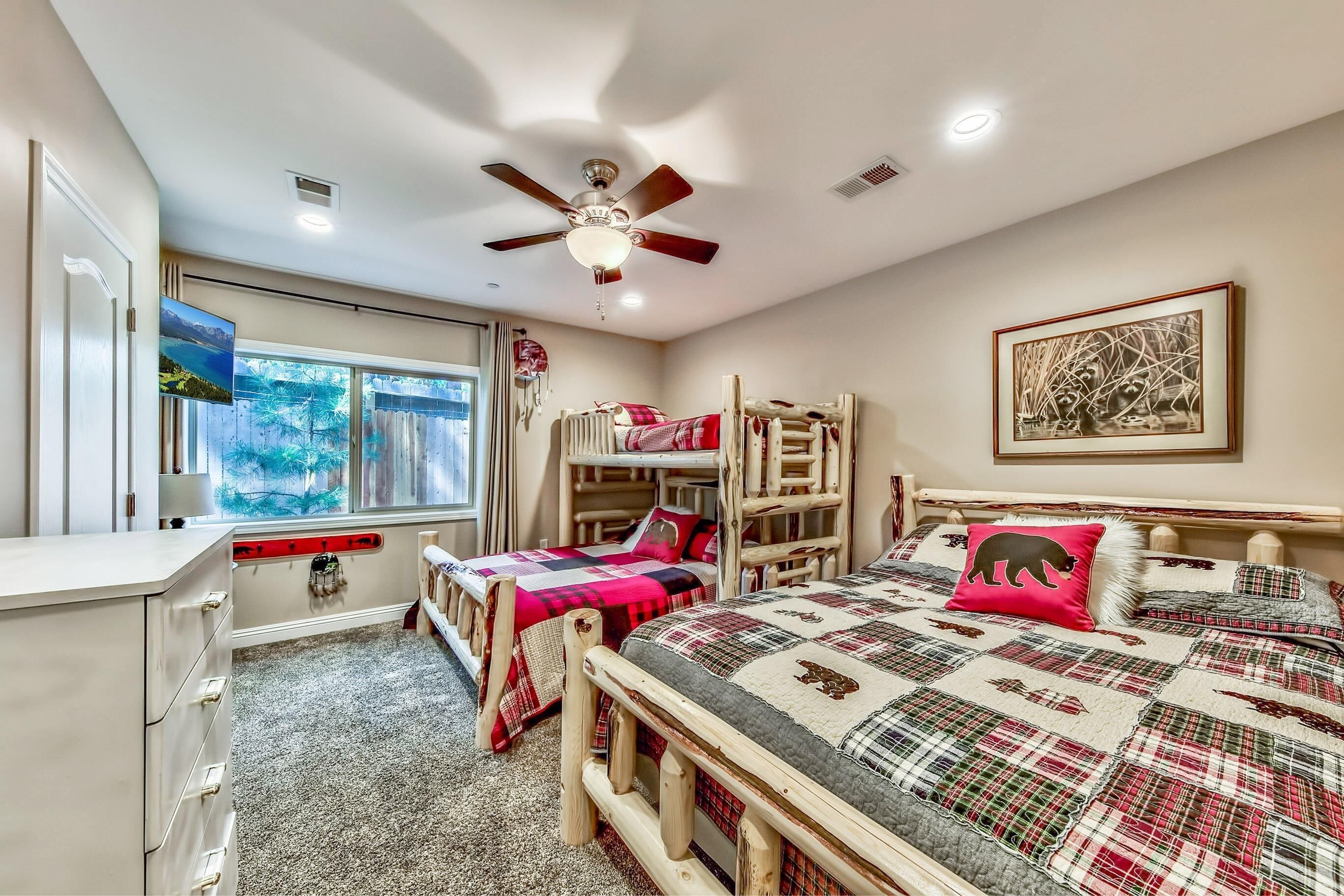 A bedroom with bunk beds, a desk, and a ceiling fan.
