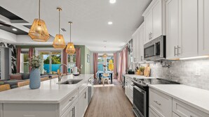 A modern kitchen with white cabinets, a central island, and pendant lighting. - Resort Pool Oasis • Game Room • Walk to Beach • Sleeps 15 (Panama City Beach)