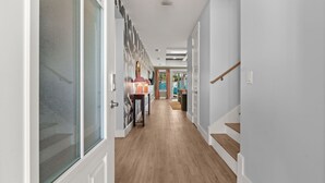 A hallway with wooden flooring, white walls, and a staircase with wooden steps. - Resort Pool Oasis • Game Room • Walk to Beach • Sleeps 15 (Panama City Beach)