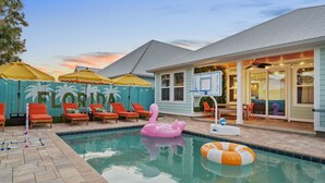 A pool area with lounge chairs, a flamingo float, and a basketball hoop. - Resort Pool Oasis • Game Room • Walk to Beach • Sleeps 15 (Panama City Beach)
