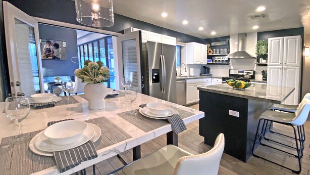 A modern kitchen with a central island, stainless steel appliances, and a dining area set for six.