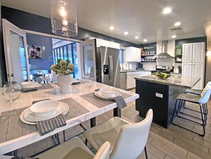 A modern kitchen with a central island, stainless steel appliances, and a dining area set for six. - Walk to Old Town ✴ 2 Masters ✴ Heated Pool & Spa (Scottsdale)