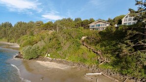 A coastal property with a wooden staircase leading to a house surrounded by dense forest. - Panoramic Promontory: Bay View Beach House (Waldport)