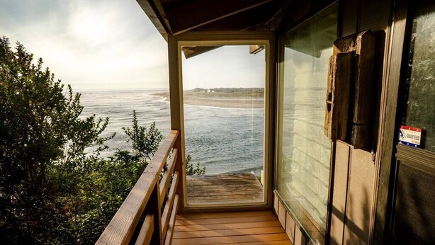 A wooden deck with a view of the ocean. - Panoramic Promontory: Bay View Beach House (Waldport)