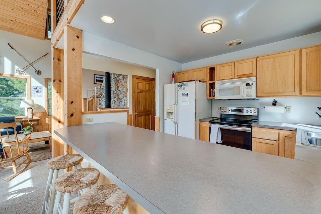 Una cocina moderna con armarios de madera, una isla grande y un microondas integrado.