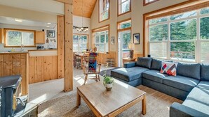 Un vaste espace de vie doté d’un grand plafond en bois, d’un canapé bleu et d’une table à manger avec des chaises.
