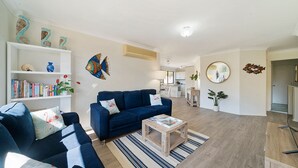 Ein modernes Wohnzimmer mit einem blauen Sofa, einem Couchtisch und einem Bücherregal voller Bücher.