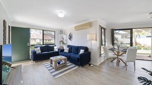 Ein modernes Wohnzimmer mit einer Sofagarnitur, einem Couchtisch und einem Essbereich mit Tisch und Stühlen.