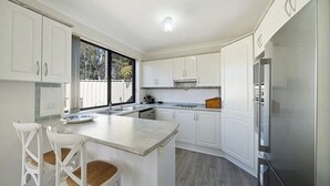 Eine moderne Küche mit weißen Schränken, einer zentralen Kochinsel und einem eingebauten Backofen.