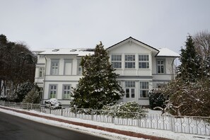 A large, two-story building with a symmetrical facade, multiple windows, and a snow-covered roof.