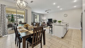Une cuisine moderne dotée d’un îlot central, un coin repas avec une table et des chaises en bois, et un espace de détente avec un canapé et un téléviseur.