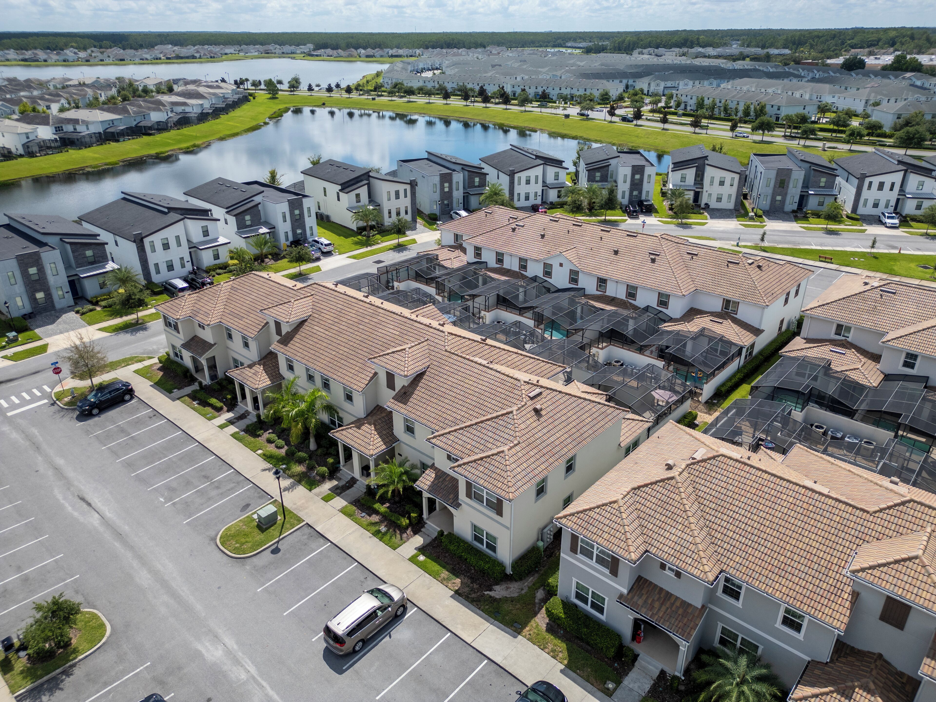 Zona residencial con casas modernas, un estacionamiento y un lago.