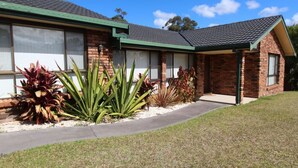A two-story brick building with a green roof and a covered porch. - Coastal Getaway by Book Jervis Bay - Free Wifi, linen & Games Room (Huskisson)