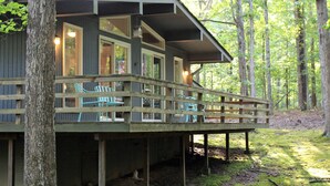 A cabin with a deck, built-in seating, and large windows. - The Hideaway- Cozy Home in the Woods (Hot Springs)