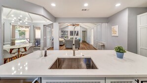A modern kitchen with a central island, white cabinetry, and a view into the living area. - Near Highways, King bed, Family-friendly, Remote work, Foosball, Grill, Games (Carrollton)