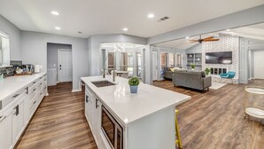 A spacious kitchen with a large island, wooden flooring, and modern appliances. - Near Highways, King bed, Family-friendly, Remote work, Foosball, Grill, Games (Carrollton)