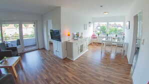 Um apartamento moderno com sala de estar, área de jantar e varanda.