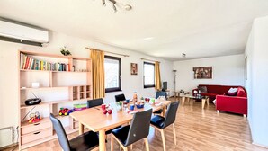 Un salon moderne comprenant un coin repas, un plancher en bois, un canapé rouge et une bibliothèque.