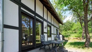 Un bâtiment moderne doté de grandes fenêtres et d’un patio aménagé avec une table et des chaises.