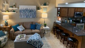A modern living room with a brown sofa, a coffee table, and a kitchen area with a bar and stools. - Luxurious, Spacious Sedona Townhome-Spectacular Views/Minutes From Attractions! (Sedona)
