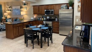 A modern kitchen with wooden cabinets, a stainless steel refrigerator, and a dining area with a table and chairs. - Luxurious, Spacious Sedona Townhome-Spectacular Views/Minutes From Attractions! (Sedona)