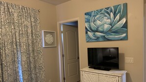A bedroom with a bed, a TV on a cabinet, a door, and a painting on the wall. - Luxurious, Spacious Sedona Townhome-Spectacular Views/Minutes From Attractions! (Sedona)