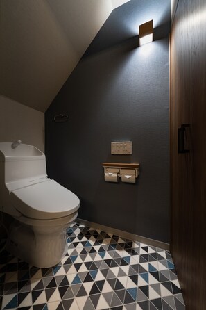 A bathroom with a toilet, a towel rack, and a wall-mounted light fixture. - Shirakabanoyado-Abeno (Osaka)