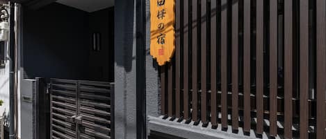 Une entrée d’immeuble avec un portail en métal et une enseigne portant des caractères japonais.