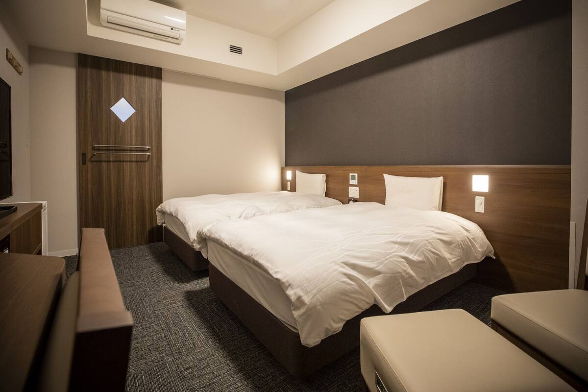 Una habitación de hotel con cama, mesita de noche y escritorio.