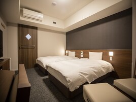 Una habitación de hotel con cama, mesita de noche y escritorio.