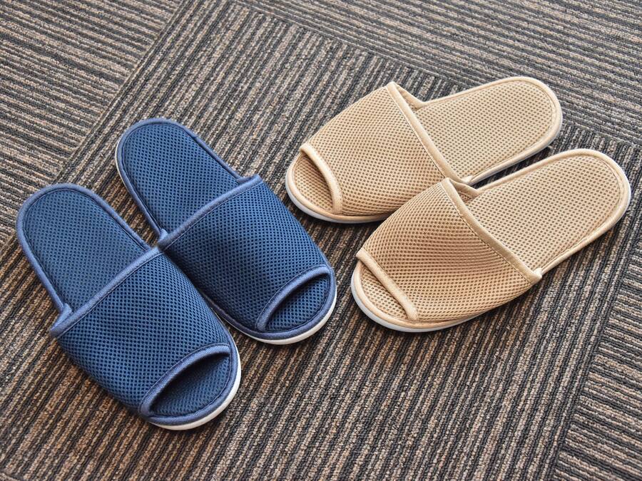 A pair of blue and beige slippers on a textured carpet.
