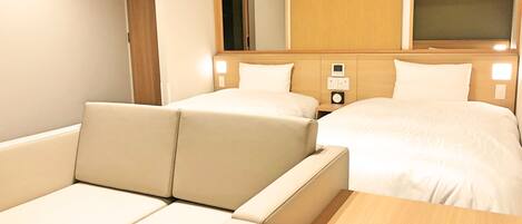 A hotel room with a sofa, a bed, a bedside table, and a mirror.
