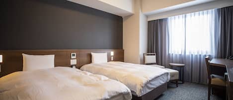 A hotel room with two beds, a desk, a chair, and a window with curtains.