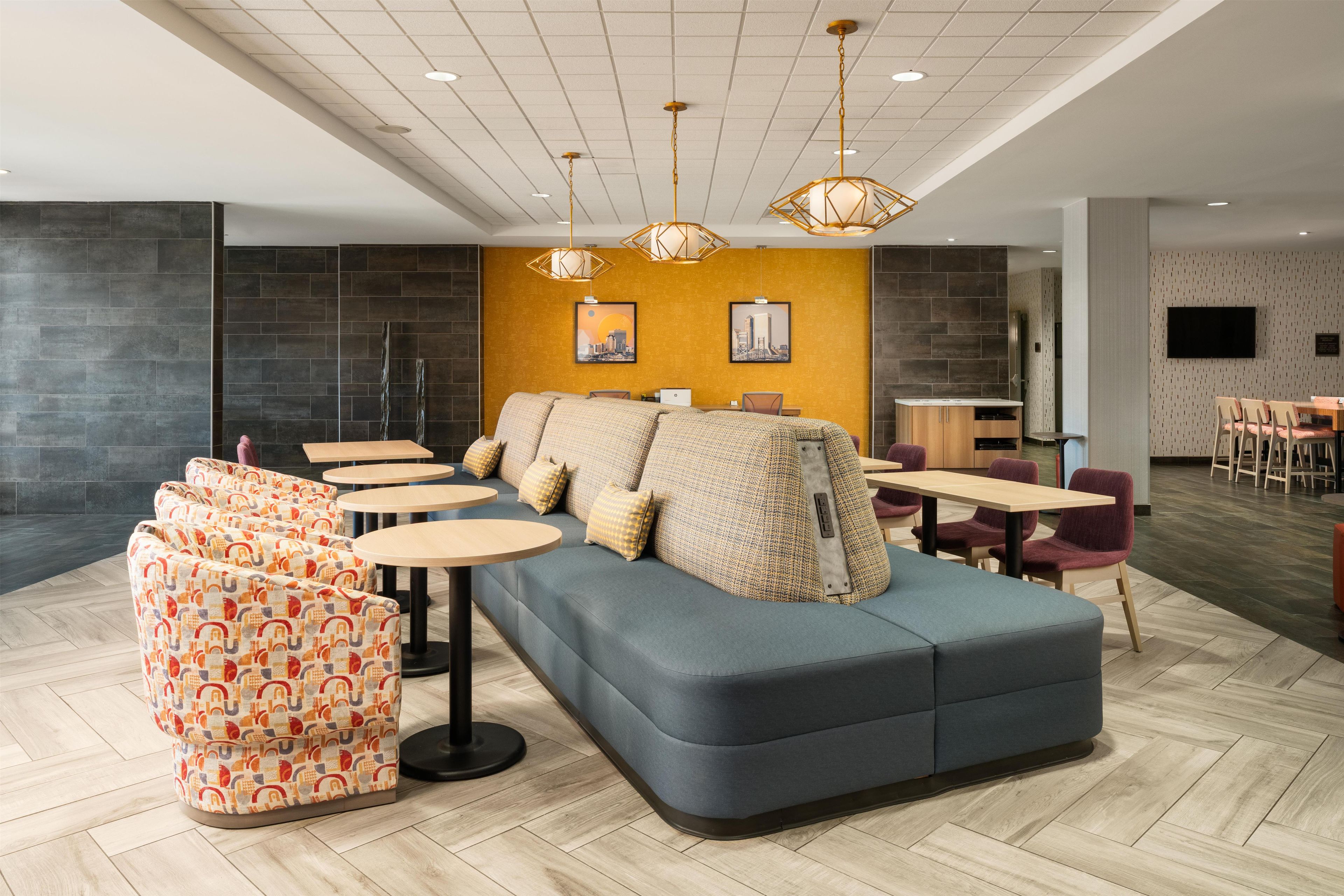 A modern lounge area with a sofa, round tables, and a television.