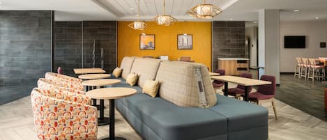 A modern lounge area with a sofa, round tables, and a television.