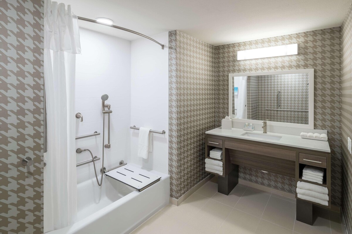 A modern bathroom with a walk-in shower, a vanity with a mirror, and a towel rack.