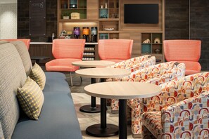 Un espace détente moderne avec un canapé, des fauteuils à motifs et des tables rondes.