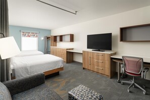 A hotel room with a bed, a desk, a television, a chair, and a small table. - Home2 Suites by Hilton Jacksonville Airport (Jacksonville)