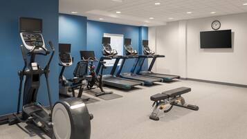 A gym with treadmills, elliptical machines, and a bench.