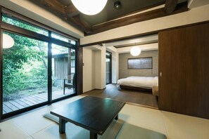 A modern room with a tatami mat, a bed, a sliding door to a balcony, and a wooden ceiling. - Fumoto Ryokan (Minamioguni)