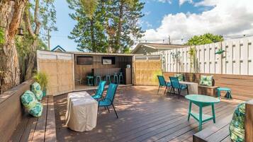 An outdoor patio area with wooden flooring, blue chairs, and a table.
