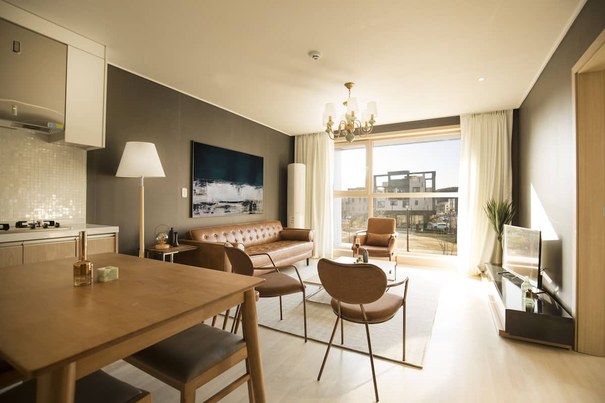 A modern living room with a sofa, chairs, a dining table, and a TV.