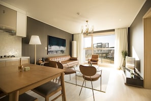 Un salon moderne comprenant un canapé, des fauteuils, une table à manger et un téléviseur.