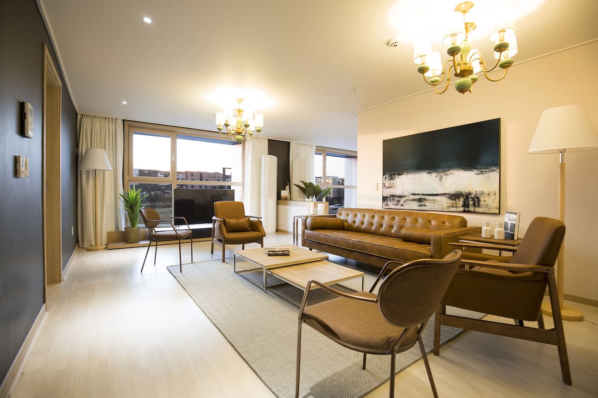A modern living room with a sofa, chairs, a coffee table, and a chandelier.