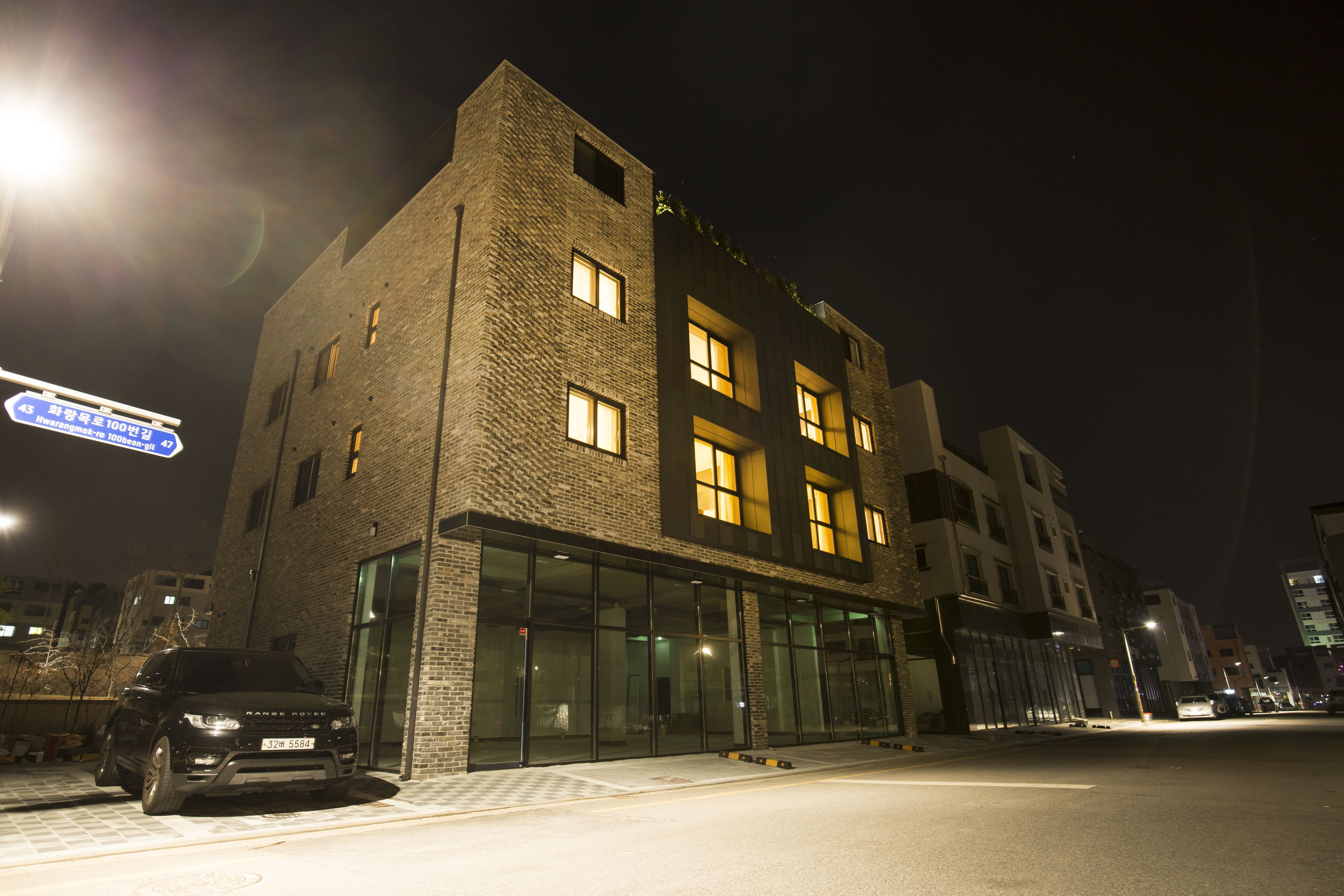 A modern building with large windows and a parking area.