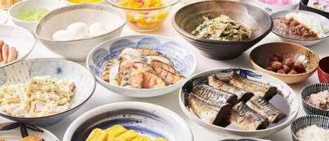 A variety of dishes including grilled fish, rice, and other foods on a table.