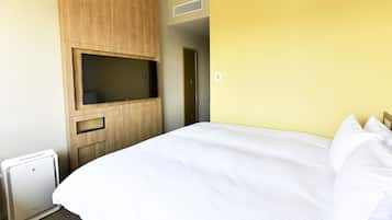 A hotel room with a bed, a TV mounted on a wooden cabinet, and a small heater.