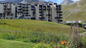 A multi-story hotel with balconies, a ski lift, and a mountain backdrop.