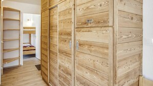 A room with a wooden wardrobe, a bunk bed, and a white door.