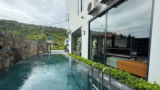 Un bâtiment moderne doté d’une piscine, de murs en pierre et d’une entrée en verre.